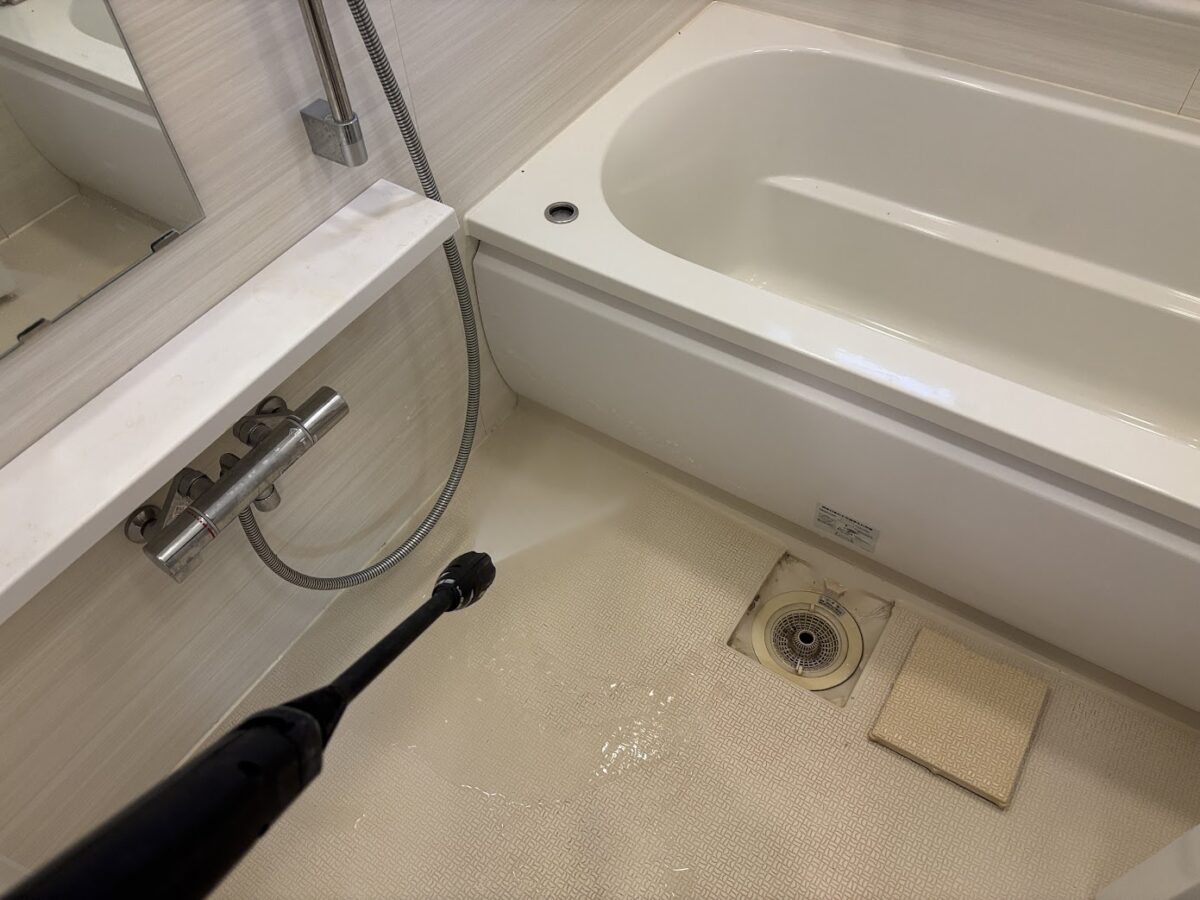 浴室の床と排水口周辺を洗浄している実作業