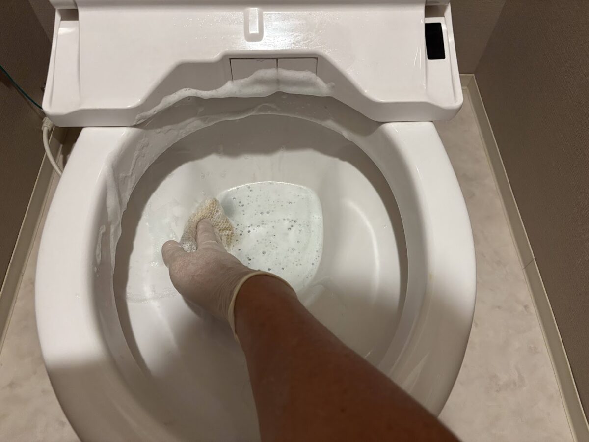 手袋を着用して便器内部を洗浄しているトイレ清掃作業