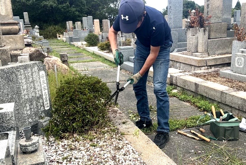 剪定バサミで植木の伸びた枝を刈り込む神戸市北区のお墓掃除作業の様子