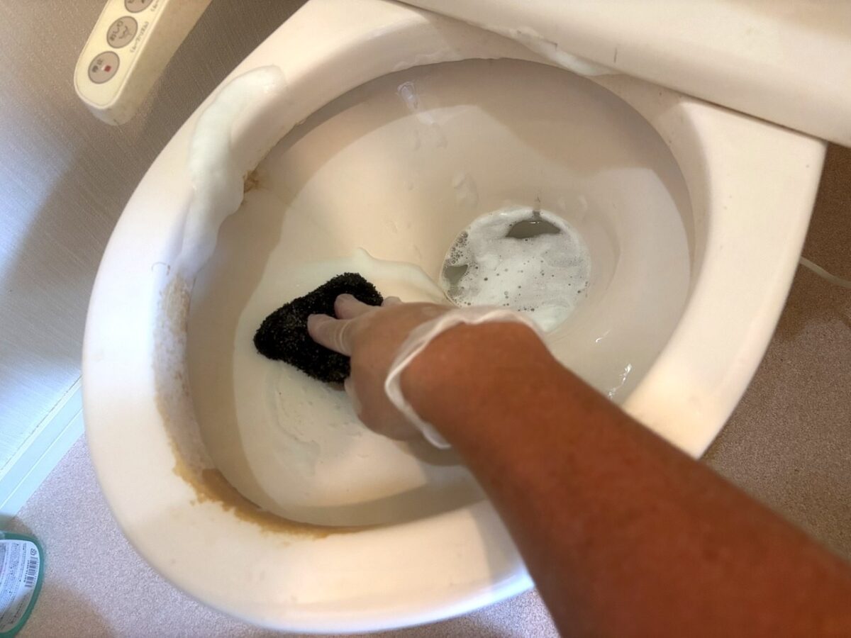 トイレ便器の内側を研磨スポンジで洗浄している手元